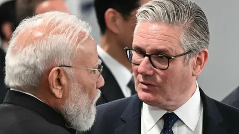 India's Prime Minister Narendra Modi (L) speaks with Britain's Prime Minister Keir Starmer ahead of a morning work meeting to "revive balanced, inclusive, and sustainable economic growth for the benefit of all" in the presence of the G7 countries, partner countries, the International Monetary Fund, and the OECD, as part of the G7 summit, in Evian, eastern France, on June 17, 2026. 