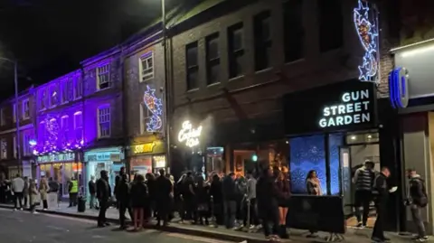 Queues and smokers outside the Cocktail Club and Gun Street Garden in Gun Street on a Friday night in Reading town centre