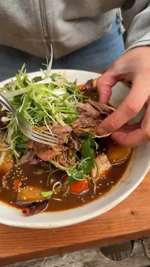 Lamb in sauce with garnish on a white plate