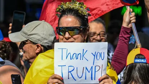 Getty Images Woman holding sign thanking Donald Trump as part of crowds celebrating in Doral neighbourhood of Miami following fall of Venezuelan president Nicolas Maduro