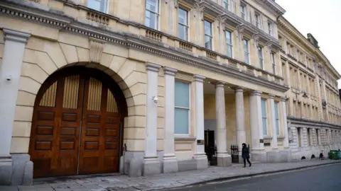 The exterior of Bristol Crown Court. It is a grand stone building, with columns at the entrance and a large arched vehicle entrance. 