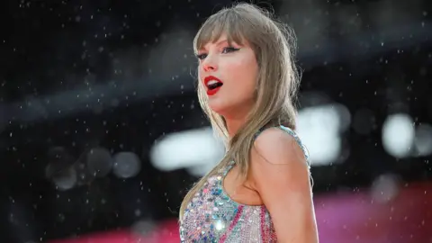 Getty Images Taylor Swift가 Eras 투어 중 함부르크에서 무대에 올라 실버 스팽글 탑을 입고 있는 모습