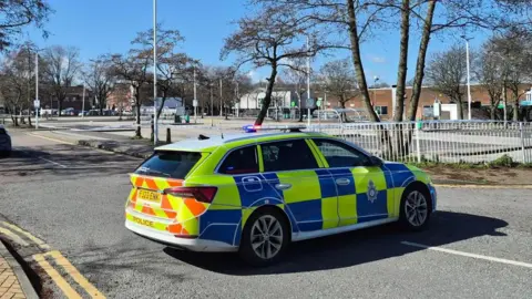 A police car outside a police cordon around an Asda supermarket car park in Sutton in Ashfield in Nottinghamshire on Saturday 14 March 2026. 