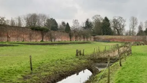 A large walled garden with red brick walls surrounding it