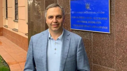 A man poses in front of a blue notice
