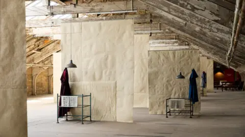 Bradford 2025 A mill room with wooden rafters and hanging fabrics