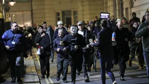 PA Media People take part in the Million Mask March anti-establishment protest at Trafalgar Square i