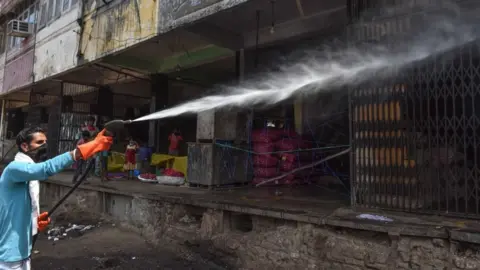 Getty Images A sanitation worker spraying disinfectant over shops in Azadpur Mandi, on May 1, 2020 in New Delhi, India.