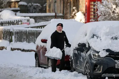 Getty Images A man shovels snow from a car in Kincardine O'Neil, Scotland, on Friday