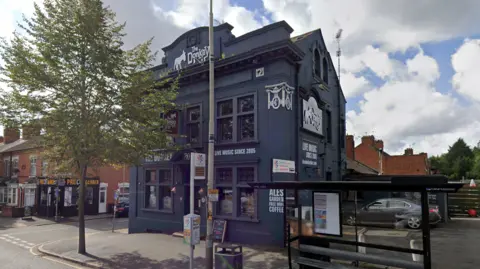 A picture of the exterior of the Donkey, a three-storey building painted grey.