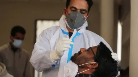 EPA A health worker takes a nasal swab sample from a man in India