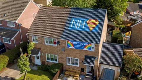 David Cheung NHS logo painted on roof of house