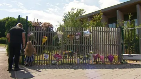 Floral tributes pinned to school fencing