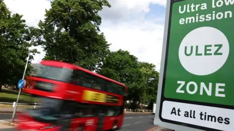 Reuters A bus goes past a Ulez sign