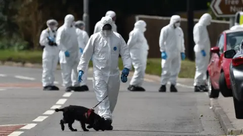 PA Media Forensics officers in white overalls comb the scene