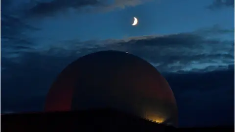 Reuters White domed nuclear power plant under a dark sky with crescent moon