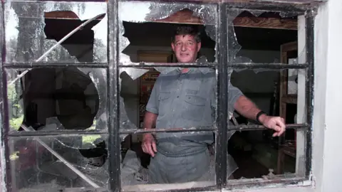 AFP Paul Retzlaff in front of a broken window at his home in Arcturus, 30km east of Zimbabwe's capital, Harare, a day after clashes broke out at his farm - 12 April 2000