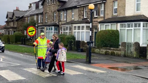 BBC/Oliver Day Bob O'Neill show mum and two children across the road