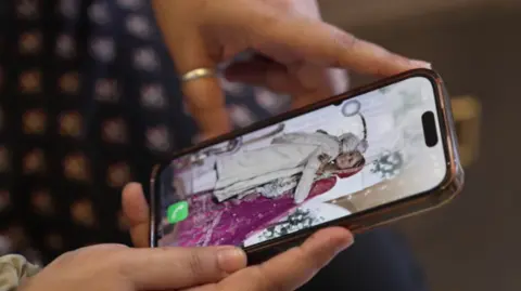Tariq Khan/BBC Hindi Picture of a phone lock screen which shows a man hugging his wife. The man is wearing a white traditional Indian wedding attire and his back is facing the camera while the woman is wearing a pink Indian lehenga. 