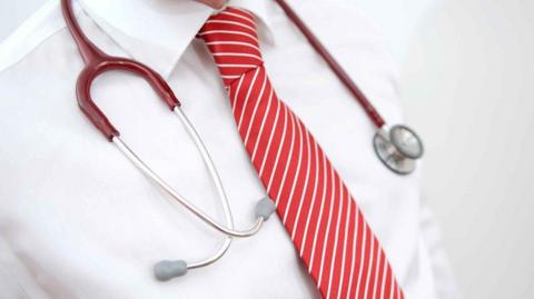 Generic picture of someone's chest wearing a white short, red tie and stethoscope