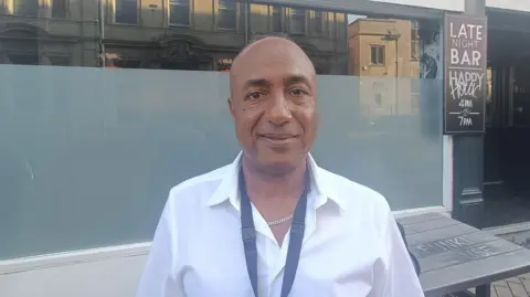 Ben Maatoug is a Personal Advisor with Bournemouth Christchurch and Poole (BCP) Council, looking towards a camera wearing a white shirt and a black lanyard.