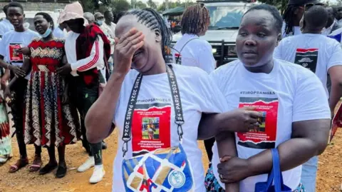 Reuters Agnes Cheptegei is supported as she mourns her daughter and Olympic athlete Rebecca Cheptegei, who died after her ex-boyfriend doused her with petrol and set her on fire, at the Moi Teaching & Referral Hospital (MTRH) funeral home, in Eldoret, Kenya September 13, 2024