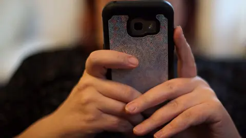 Close-up of hands holding a mobile phone with the person holding it out of vision behind