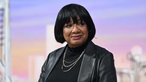 Diane Abbott sitting in the Sunday with Laura Kuenssberg TV studio, wearing a black leather jacket over a black top