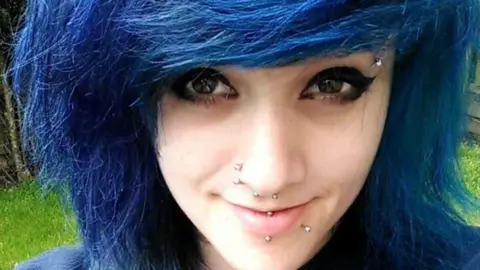 Handout Picture of a headshot of Charlotte wearing a blue jumper and blue hair in a bob 