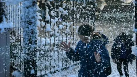 A child wearing a blue coat walking in fake now.