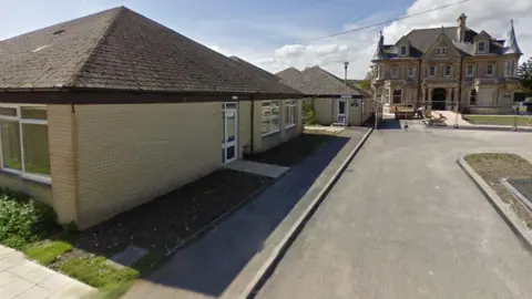 A Google Street View of Dorchester Learning Centre, a single-storey yellow brick building. In the distance is a historic looking house.
