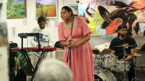 A band are on the stage at Common Ground. The singer, keyboard player and drummer are poised to play.