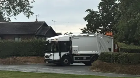 Local Democracy Reporting Service A bin lorry pulling out of the junction opposite Castle Green's Hawthorn Meadows development in Buckley -