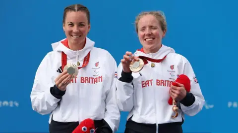 Para-cyclists Corrine Hall and Lora Fachie pose on the podium with their bronze medals at the Paris Paralympics