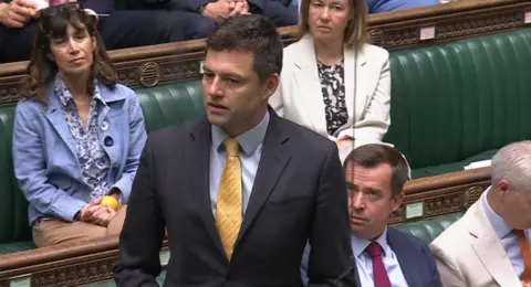 UK PARLIAMENT A man in a suit with a yellow tie. 