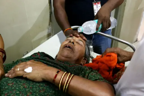 Niharika Kulkarni/AFP A hospital worker pours water on the face of a patient suffering from heatstroke at a government hospital during an intense heatwave in Varanasi on May 30, 2024. 