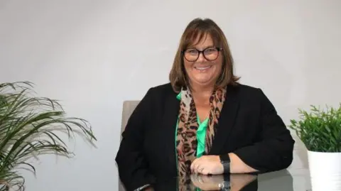 Acorns Nurseries Cherie Wilson, Acorns Nurseries Director, smiling looking at the camera. She is seated at a table