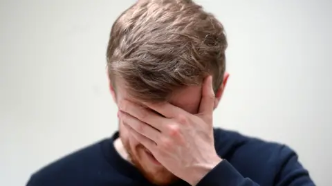 A man hides his face with his hand in a scene of distress.