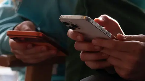 AFP via Getty Images Two people on their mobile phones