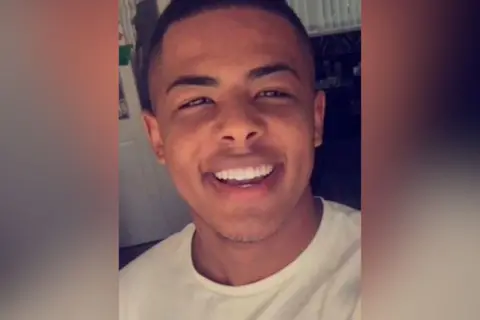 Breon Simms. He is smiling and wearing a white t-shirt.