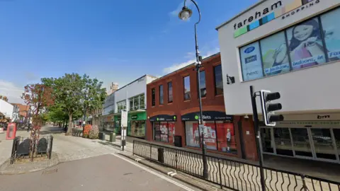 Fareham high street, a pedestrianised road with shops, plants and a red phone box.