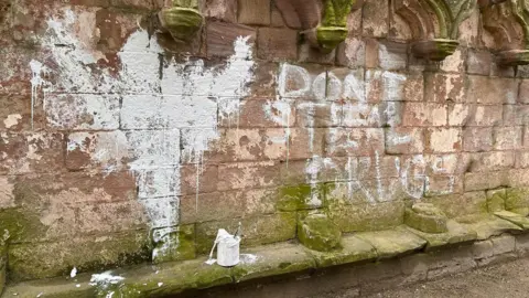 North Yorkshire Police Graffiti painted on abbey walls, with paint tin in front