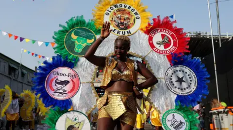 Reuters A woman wears an outfit displaying the names and emblems of the Fanti Carnival associations