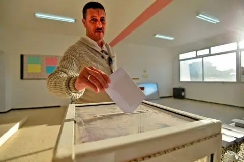 AFP An Algerian man casts his vote on 12 December in Algiers.