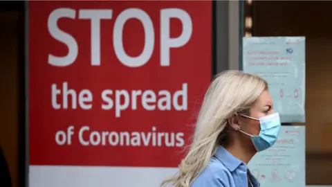 PA Media Woman wearing face mask outside hospital