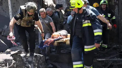 Emergency services in Dnipro carry a wounded person out of a building damaged in a Russian missile attack, 24 June 2025