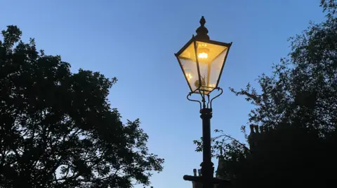 A gas lamp lit up at night in The Park, Nottingham