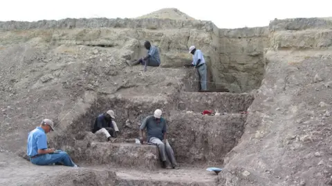 Human Origins Program, Smithsonian Five men work in a stepped excavation area
