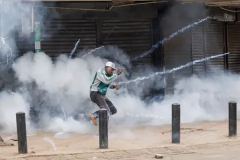 AFP A protester runs to get away from a detonating tear gas canister during a demonstration against the government in Nairobi, Kenya, on 8 August 2024