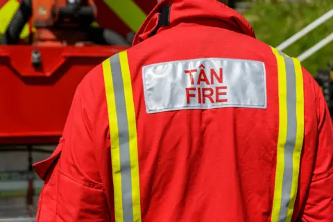 Getty Images The back of an orange jacket that reads Fire, in English, and Tan, in Welsh 